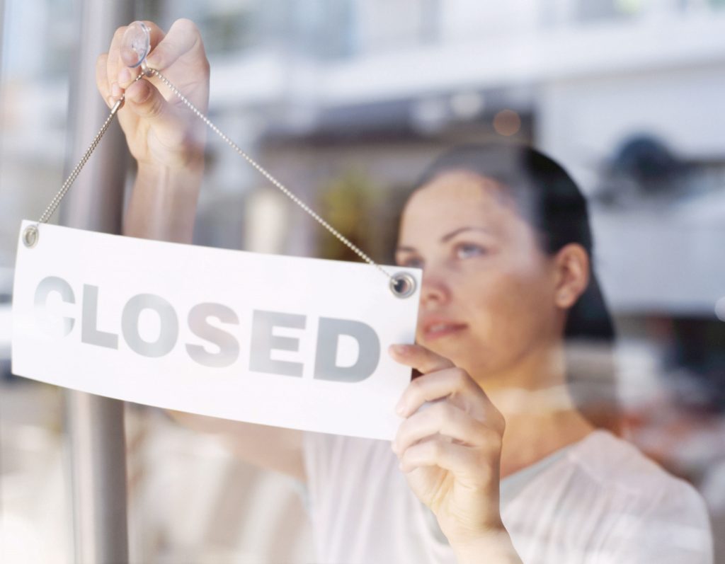 Business Owner Hanging a Closed Sign